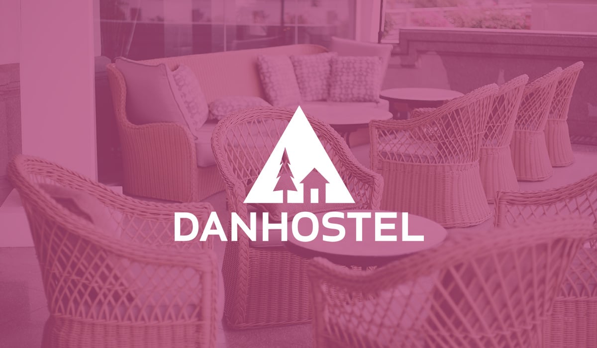 The modern outdoor lobby of a hotel, filled with various light rattan furniture, showcasing the logo of the tamigo customer Danhostel in the foreground.