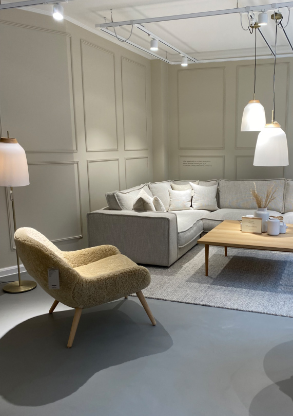 Green chair and grey sofa in a showroom of tamigo customer Bolia. 