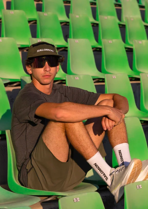 Man sitting in sports stadium wearing clothes made by tamigo custom Salomon.