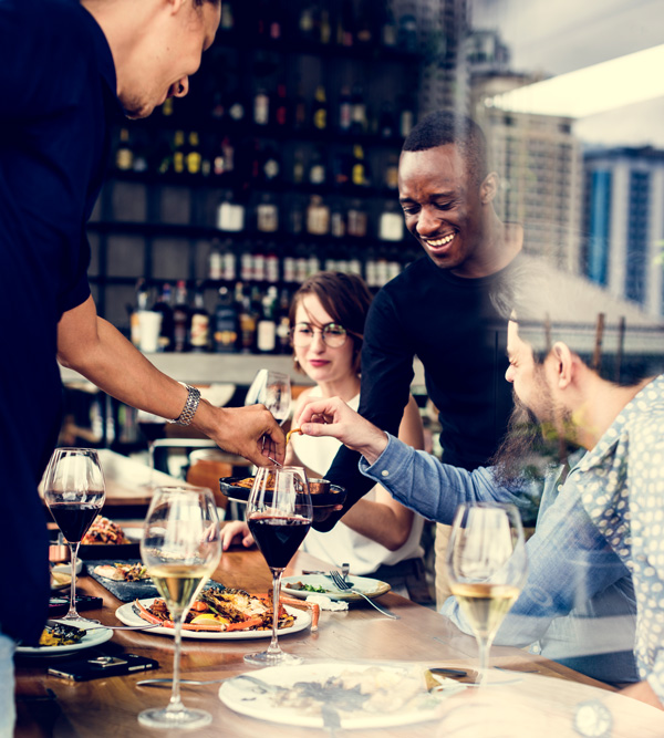 Zwei Kellner bedienen zufrieden zwei Gäste in einem Restaurant.