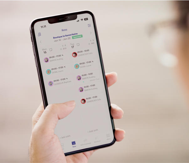 Een persoon die een telefoon vasthoudt met de planningssoftware voor het personeel open, met het rooster van de medewerkers voor boetiek 1A op maandag 16 januari en dinsdag 17 januari.